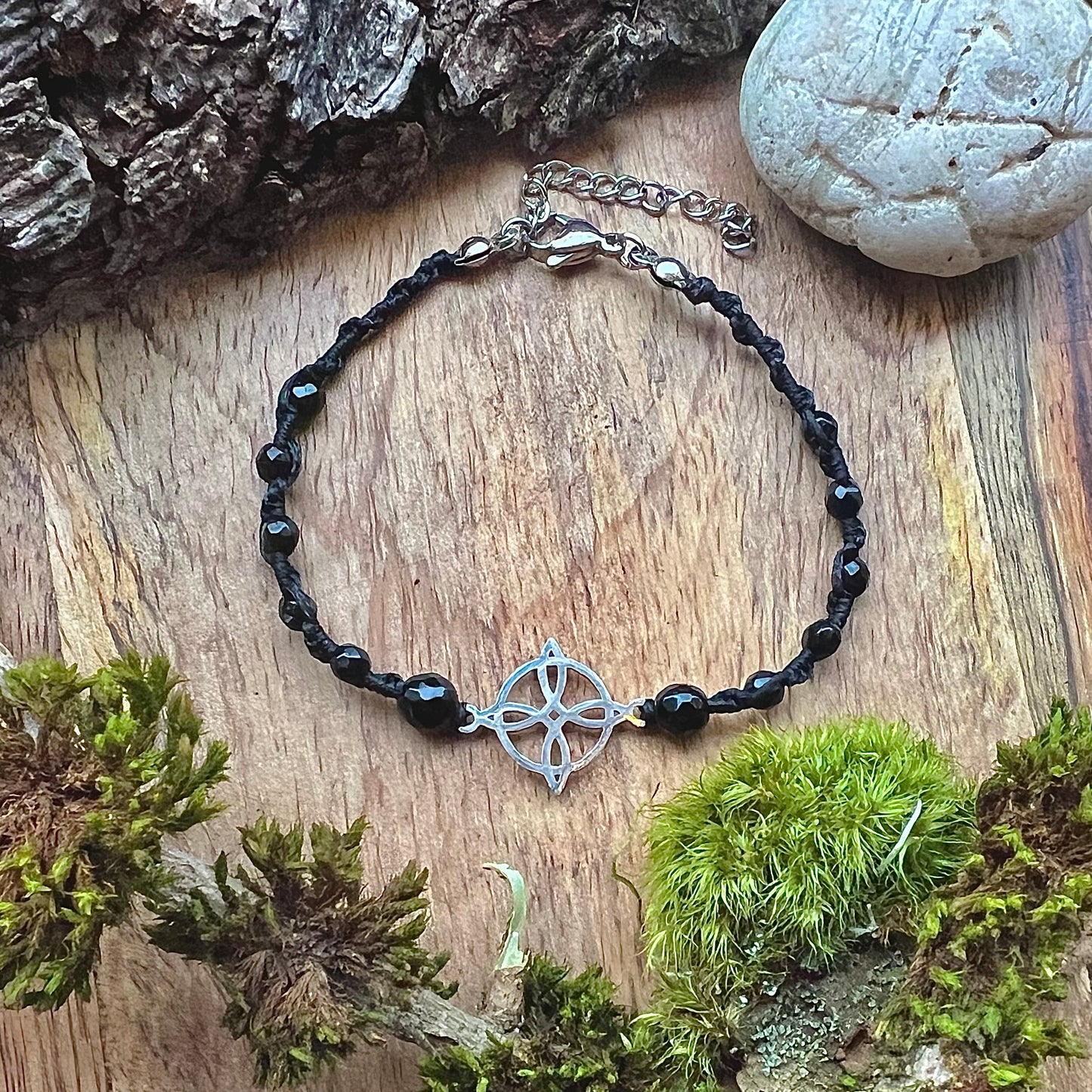 Hand-knotted bracelet with faceted onyx and Celtic lucky knot