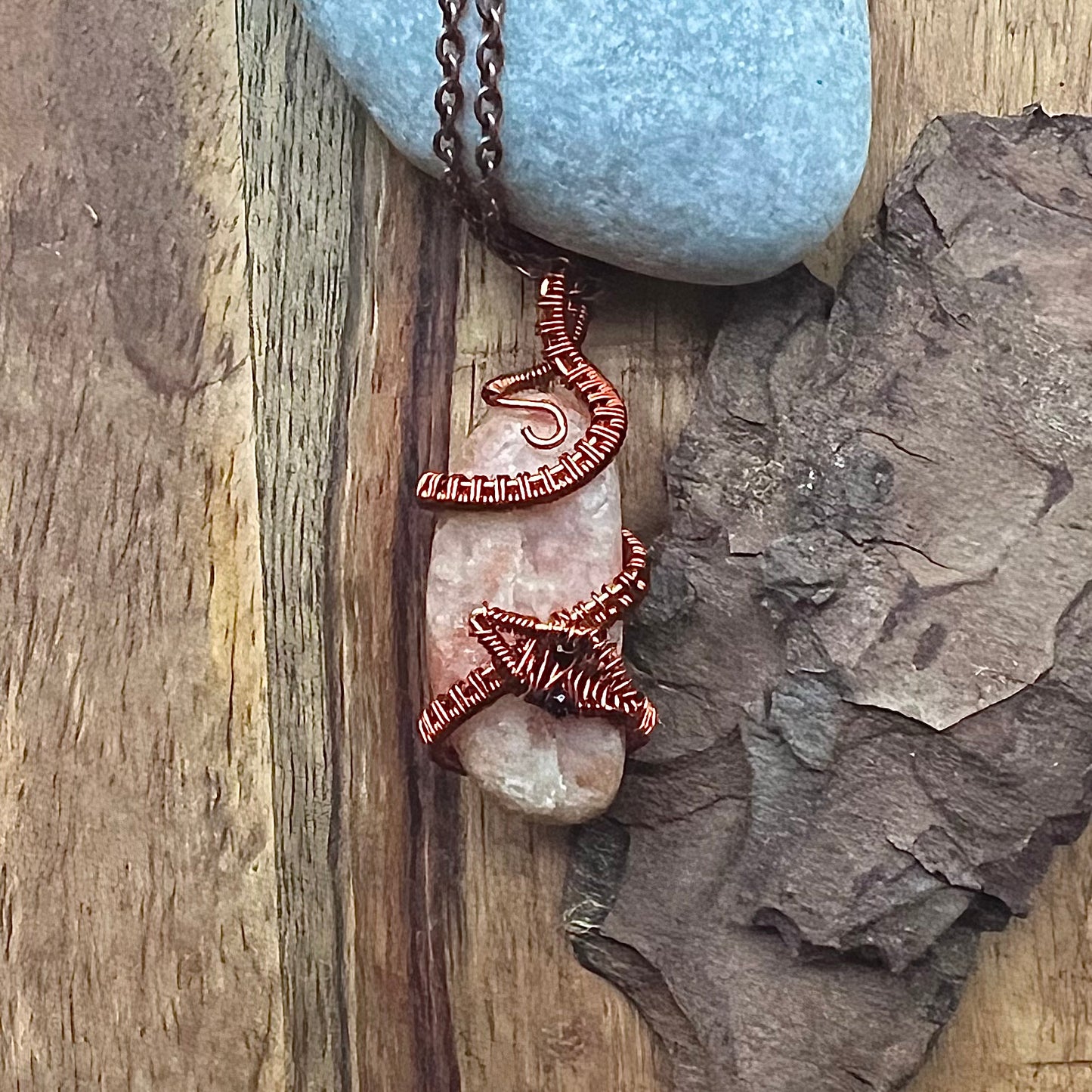 Necklace with peach colored sunstone and copper snake