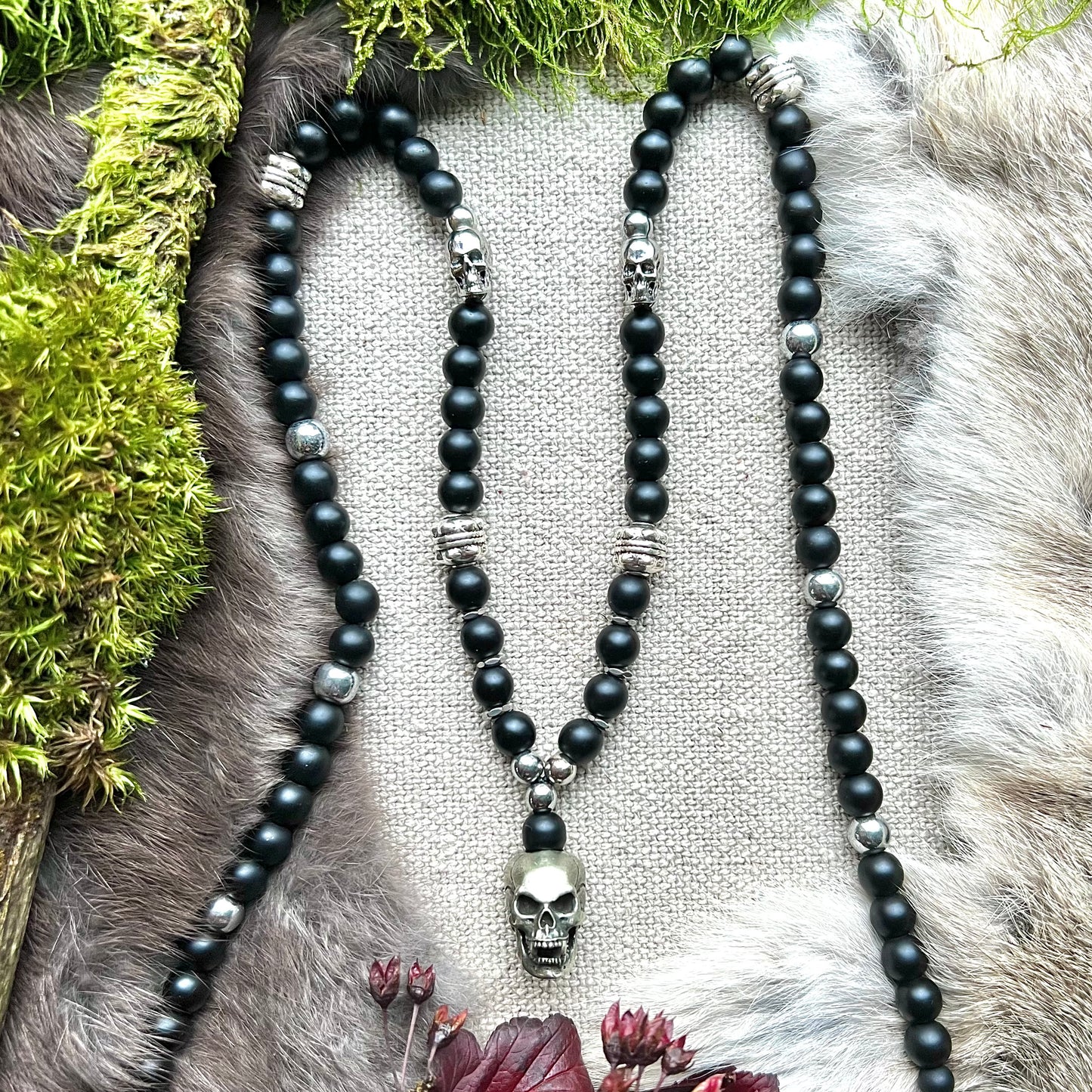 Necklace of black frosted glass with steel and brass skulls