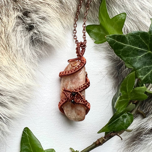 Necklace with peach colored sunstone and copper snake